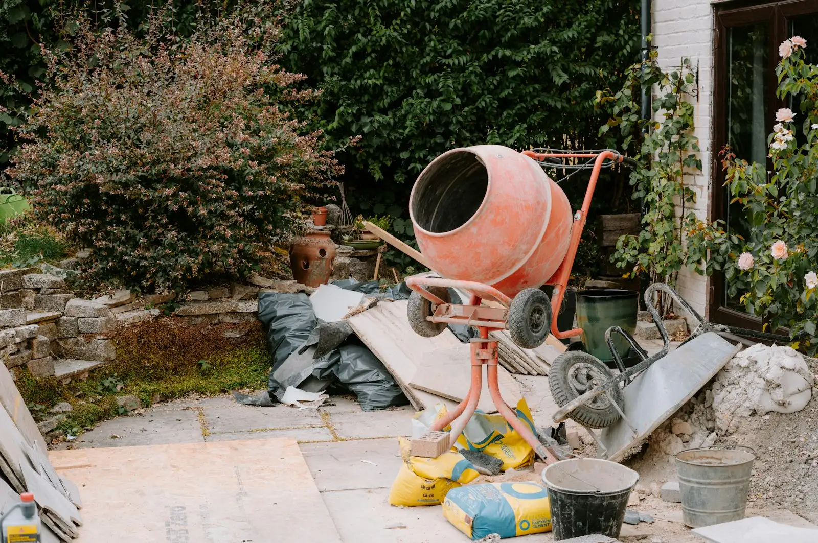 Avant : Terrasse en chantier avec bétonnière et sacs de ciment