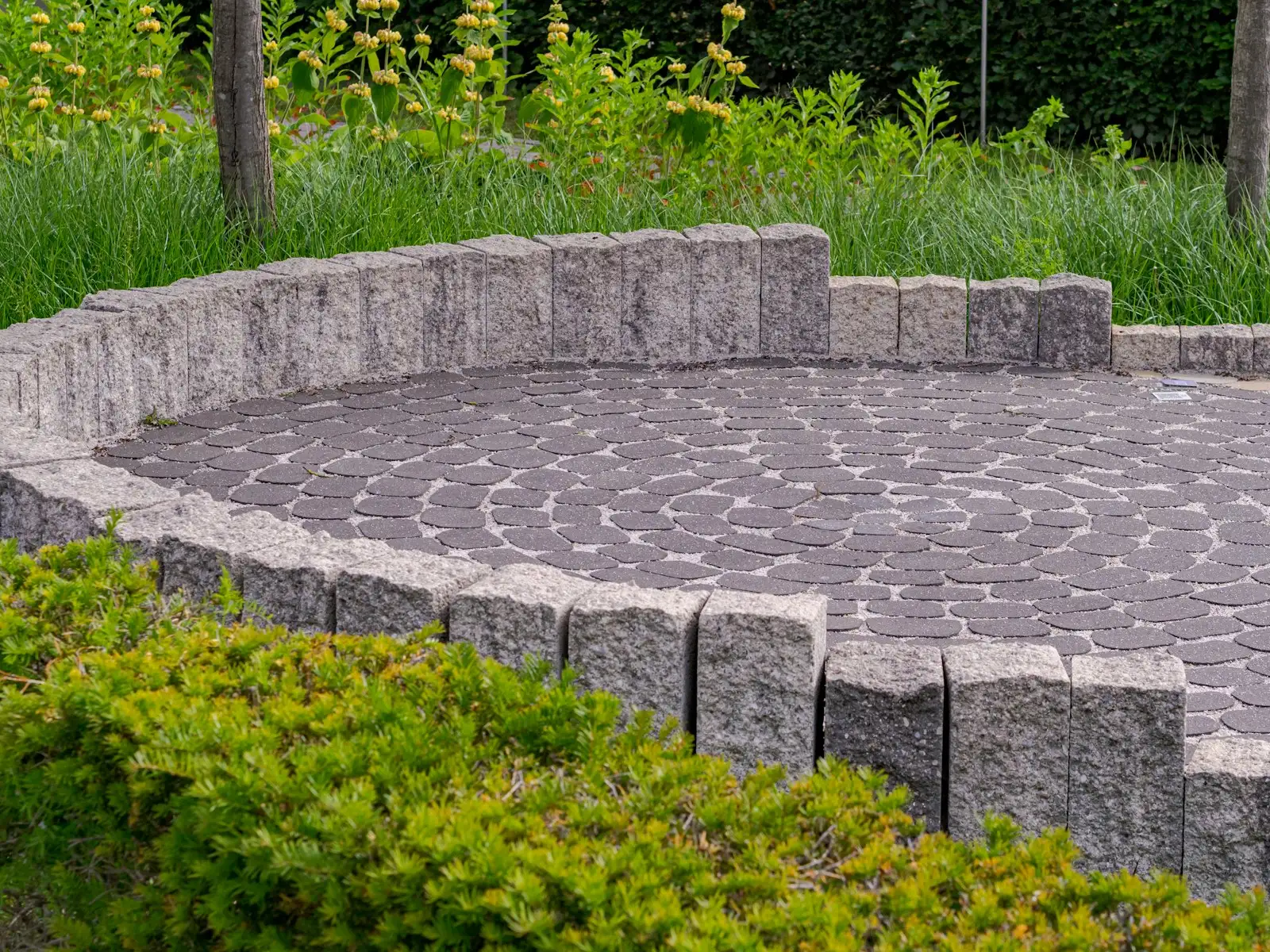 Terrasse ronde pavée bordée d’un muret en pierre
